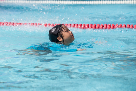 7 years old healthy Asian kid swimming training in clean swimming pool at sport club with copy spaceの写真素材