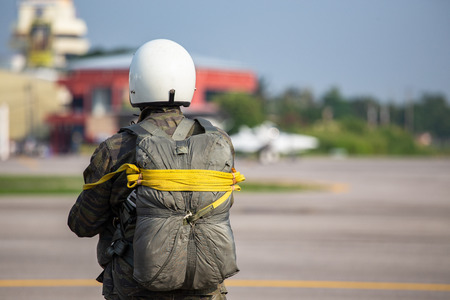 Police paratrooper in camouflage uniform and helmet with T-10 static line parachute  and equipment standby at airfield with copy spaceの写真素材
