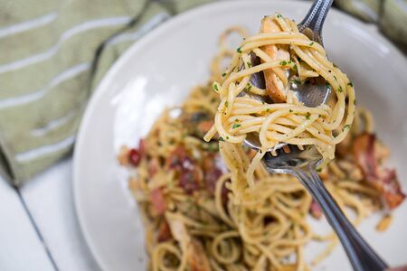 Spaghetti with bacon and basil on on a fork roll.の写真素材