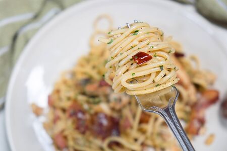 Spaghetti with bacon and basil on on a fork roll.の写真素材