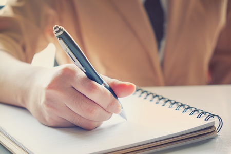 Business woman analyzing investment charts on blank notebook at morning time.の写真素材