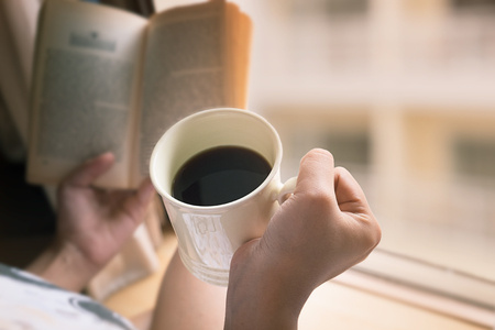 Young girl holding coffee cup and book in the morning time,Vintage tone.の写真素材