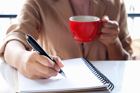 Business girl Hand write note and holding cup of coffee,vintage effect in the morning time.の写真素材