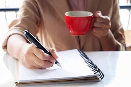 Business girl Hand write note and holding cup of coffee,vintage effect in the morning time.の写真素材
