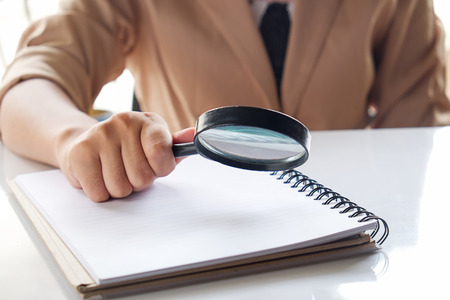 Business woman looking through a magnifying glass to documents note,vintage effect.の写真素材