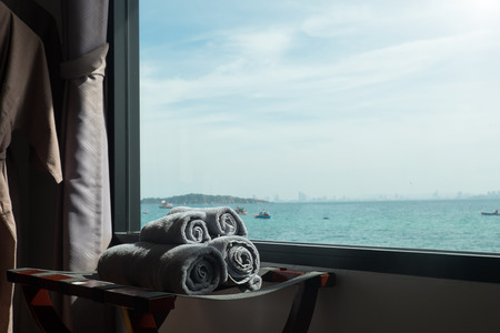 rolled towel in room with sea scape on windows dark tone and vintage tone, holiday concept.の写真素材