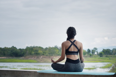 Woman doing yoga fitness exercise outdoor mountains landscape with vintage tone.の写真素材