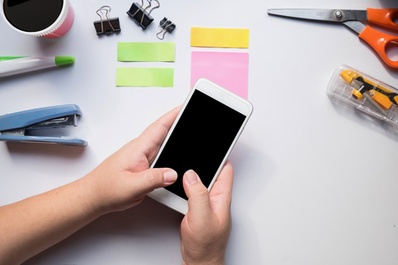 Hand using smartphone on office desk, workplace concept.の写真素材