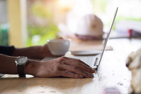 Laptop and coffee cup in man's hands, vintage effect tone with outdoor cafe.の写真素材