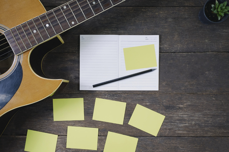 Desk of song composer for a work songwriter with a guitar and notepad on wood table with vintage tone.の写真素材