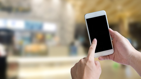 Hand using empty screen of smartphone for present application on shopping mall background 16:9 size.の写真素材