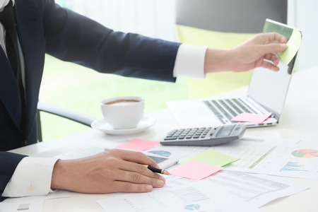 Business man using  note stick memo and report finance paper on office table.の写真素材