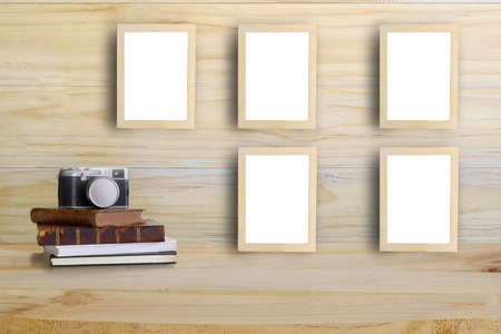 photo frames on wooden wall and camera,retro book on a wood desk with Mock up and copy space.の写真素材