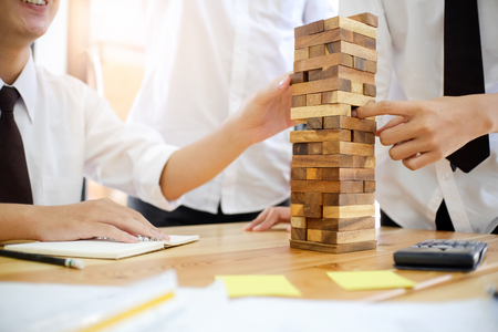 Architectural project concept,engineering playing a blocks wood tower game on blueprint or planning architectural project in engineer, office.の写真素材