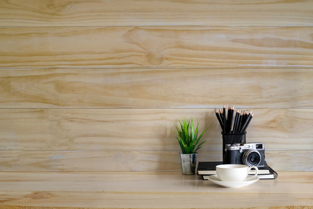 office supplies, camera,coffee cup plant decoration and pencils on wood desk and wood wall with empty copy space for present something.の写真素材