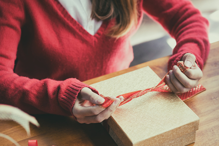 woman holding Christmas presents laid and close gift box on a wooden table background.の写真素材