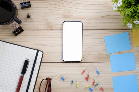 Empty screen smartphone and office supplies on wood work table.の写真素材