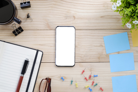 Empty screen smartphone and office supplies on wood work table.の写真素材