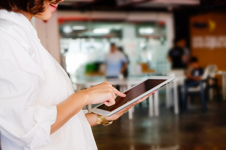 Smiling woman using tablet in office cropped shot photo.の写真素材