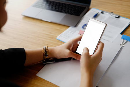 Cropped shot of hands businesswoman using smartphone mockup at wood desk.の写真素材