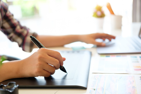 Cropped shot of graphic designer working with digital pen on tablet in artist workplace.の写真素材