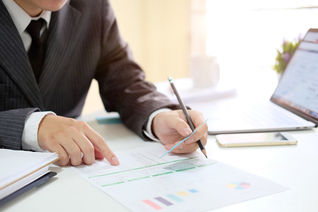 Business man analysis data in paper document with laptop computer in office.の写真素材