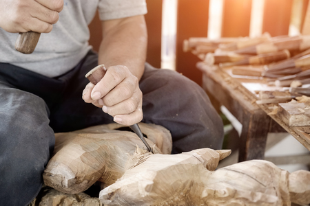 Closeup Old man Hands of craftsman wooden carve with a gouge in the hands on the workbench in carpentryの写真素材