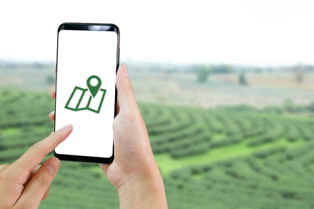 Closeup hands using smartphone open GPS and GIS application with agriculture field industry farm technology.の写真素材