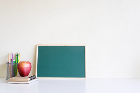 Education stuff background of frame board, model apple fruit, jar of colour pencil and notebook paper with copy space.の写真素材