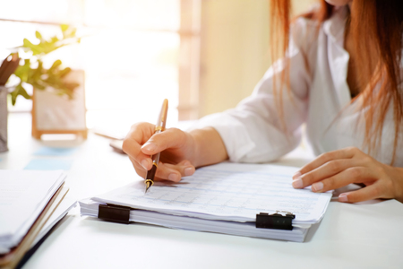 Close up audit woman calculate on paper document financial data.の写真素材