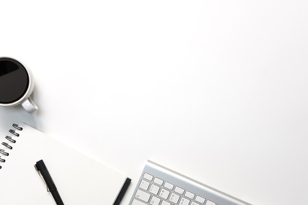 Modern white office desk table with keyboard computer, coffee, pen and notebook paper with workspace top view workspace.の写真素材
