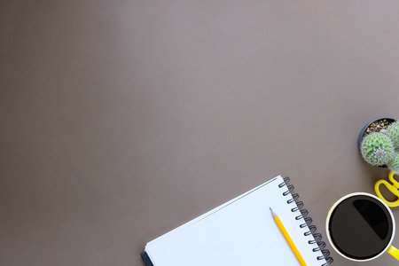 Office desk coffee cup and pencil with notepad paper on brown table background, Top view workspace.の写真素材