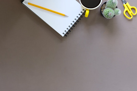 Office desk coffee cup and pencil with notepad paper on brown table background, Top view workspace.の写真素材