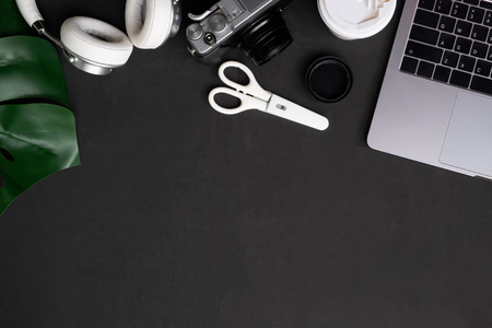 Artist table Computer, camera, coffee and headphones on black office table with top view and copy...