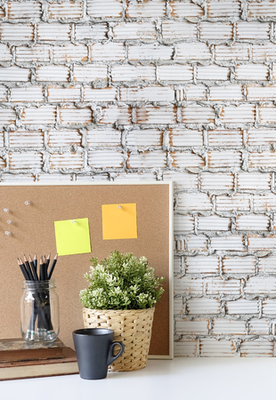 Stylish table Board   book, pencil and coffee mug on table with brick wall.の写真素材