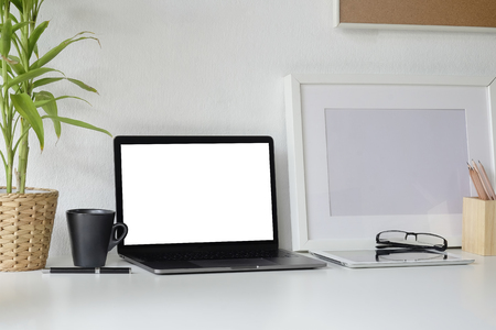 Mockup laptop computer, pencil, book and photo frame on white desk with office supplies.の写真素材