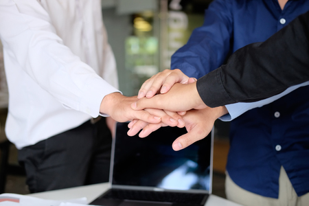 Close up young business people putting their hands together. Stack of hands on office workplace. Unity and teamwork concept.の写真素材