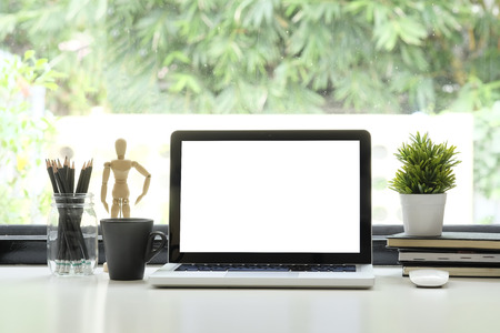 Workspace laptop computer, coffee, pencil and plant decoration with big window and nature on background.の写真素材