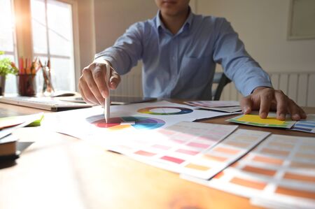 Graphic designer and colour swatches with pens on a desk. young man drawing.の写真素材