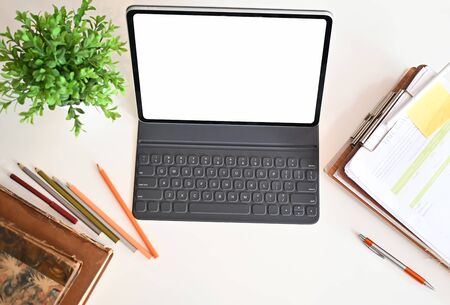 Creative desk workspace with mockup tablet computer and office equipment on black table, top view.の写真素材