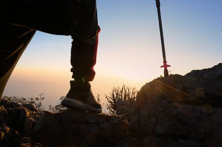 Closeup man hiking at sunset silhouette mountain with travel lifestyle adventure concept.の写真素材