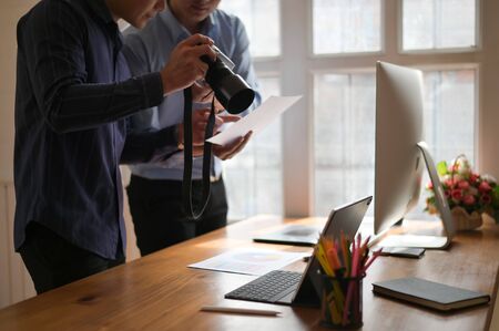 Photographer Colleagues discussing photographs at creative office, Photo editor job.の写真素材