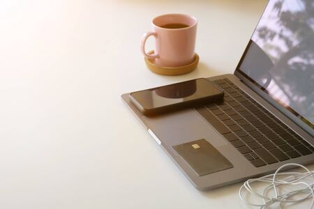 Credit card and smartphone on laptop computer and coffee cup with office table.の写真素材