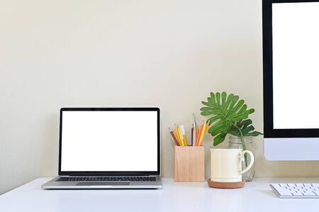 Laptop computer and PC on office desk, Workspace with mockup.の写真素材