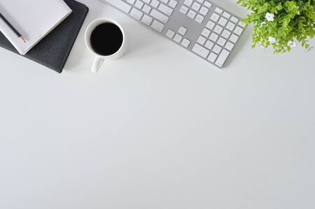Flat lay top view office desk. Workspace with keyboard and office supplies with coffee on white background.の写真素材