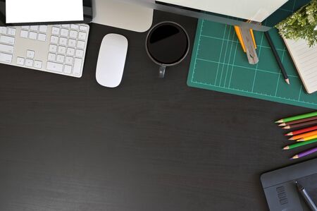 Creative desk workspace with mockup tablet computer and office equipment on black table, top view.の写真素材