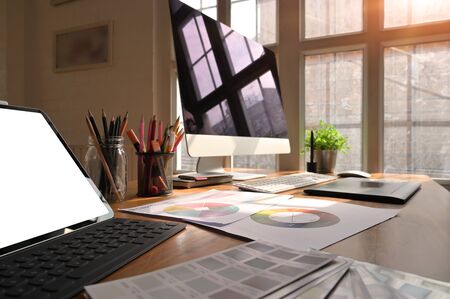 Creative workspace computer and tablet with colour space on artist desk.