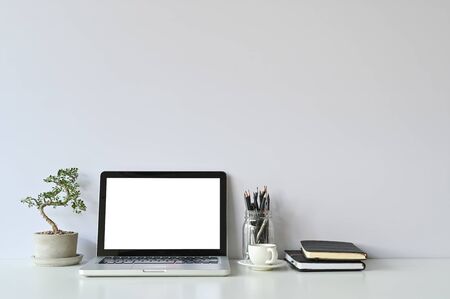 Mockup laptop computer and office supplies and small bonsai on workspace.の写真素材