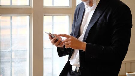 Businessman using mobile phone device with cropped shot of photo.の写真素材