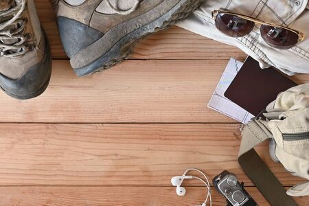 Travel accessories set on wooden desk hiking boots, jacket, backpack, map, camera and sunglasses with copy space.の写真素材